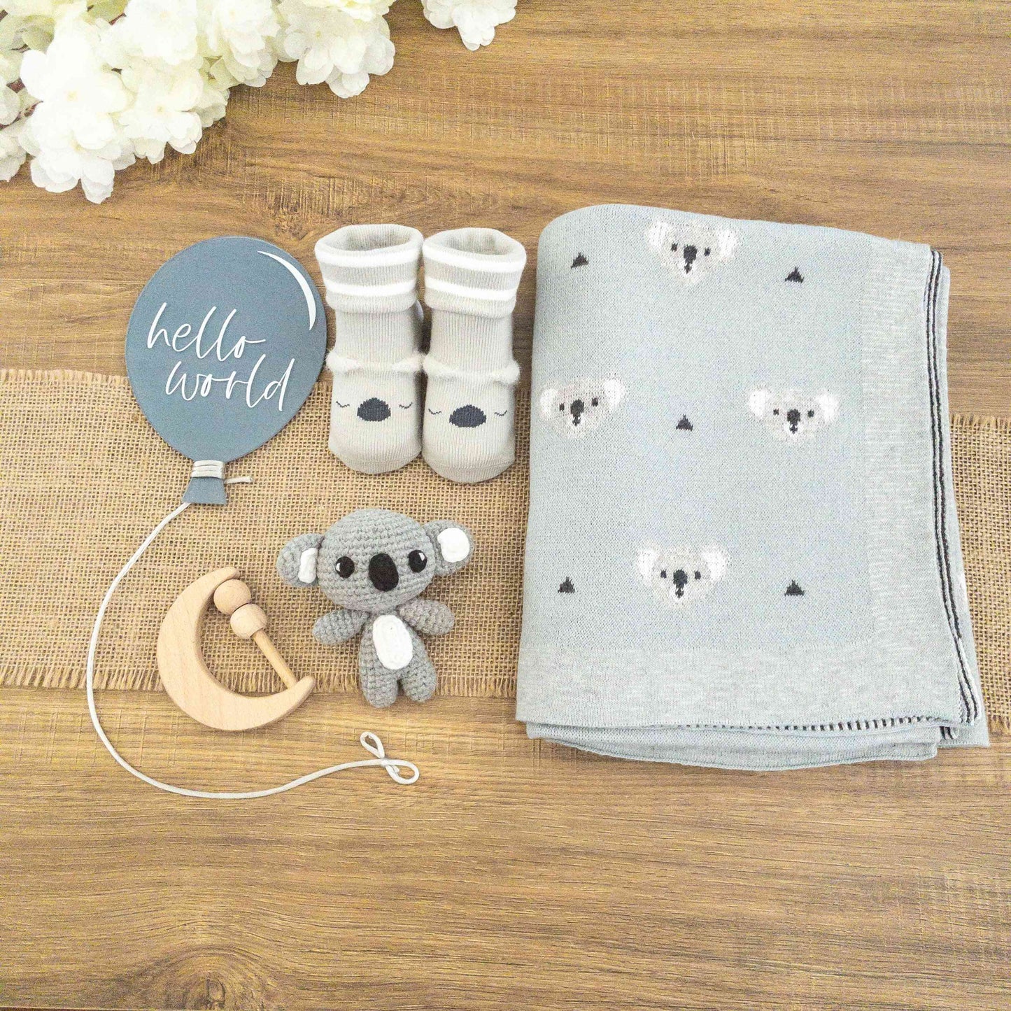 scatola con set regalo neonato koala con coperta cotone azzurra, pupazzetto amigurumi koala, calzine antiscivolo koala, sonaglio sensoriale e insegna palloncino acrilico Hello World blu