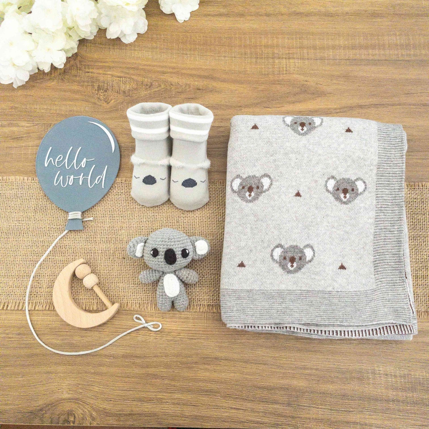 scatola con set regalo neonato koala con coperta cotone grigia, pupazzetto amigurumi koala, calzine antiscivolo koala, sonaglio sensoriale e insegna palloncino acrilico Hello World blu