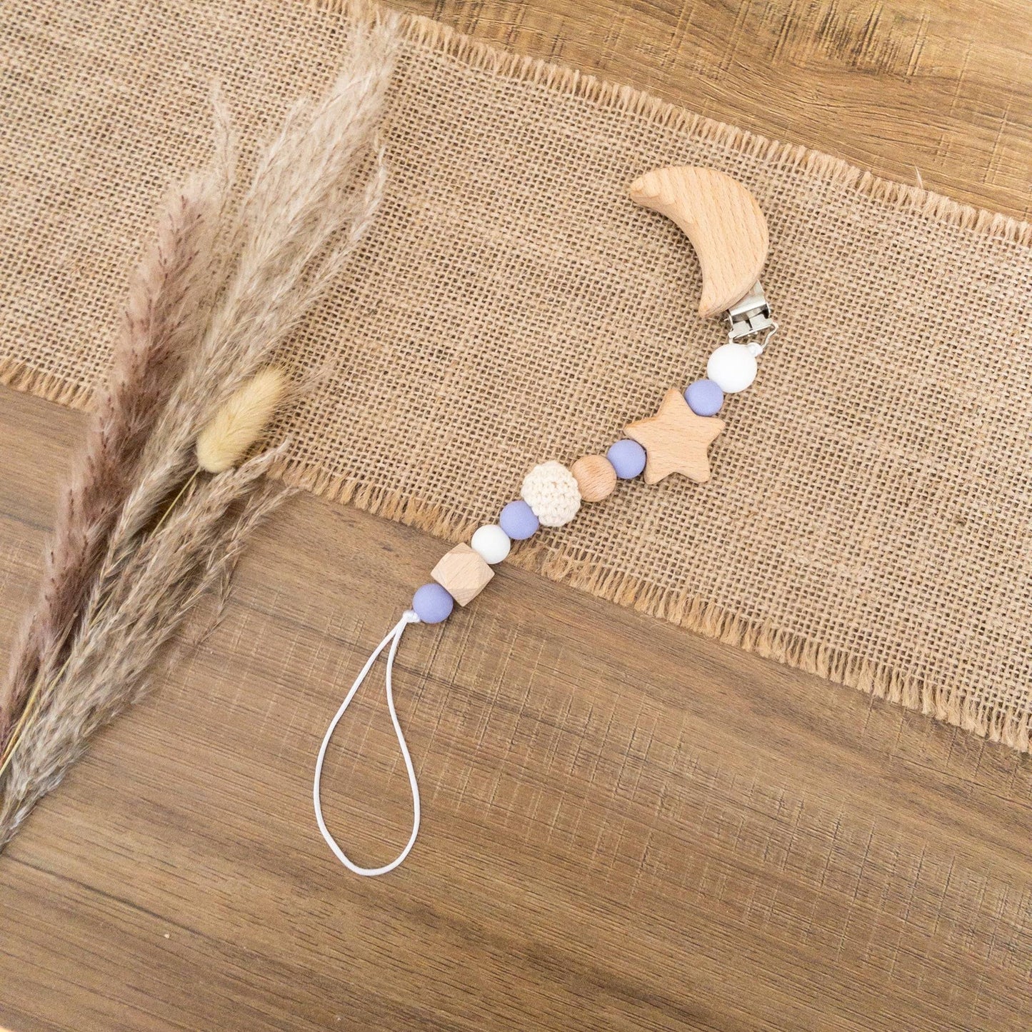 dettaglio catenella clip ciuccio con luna, stelle e colori lilla e bianco di legno e silicone