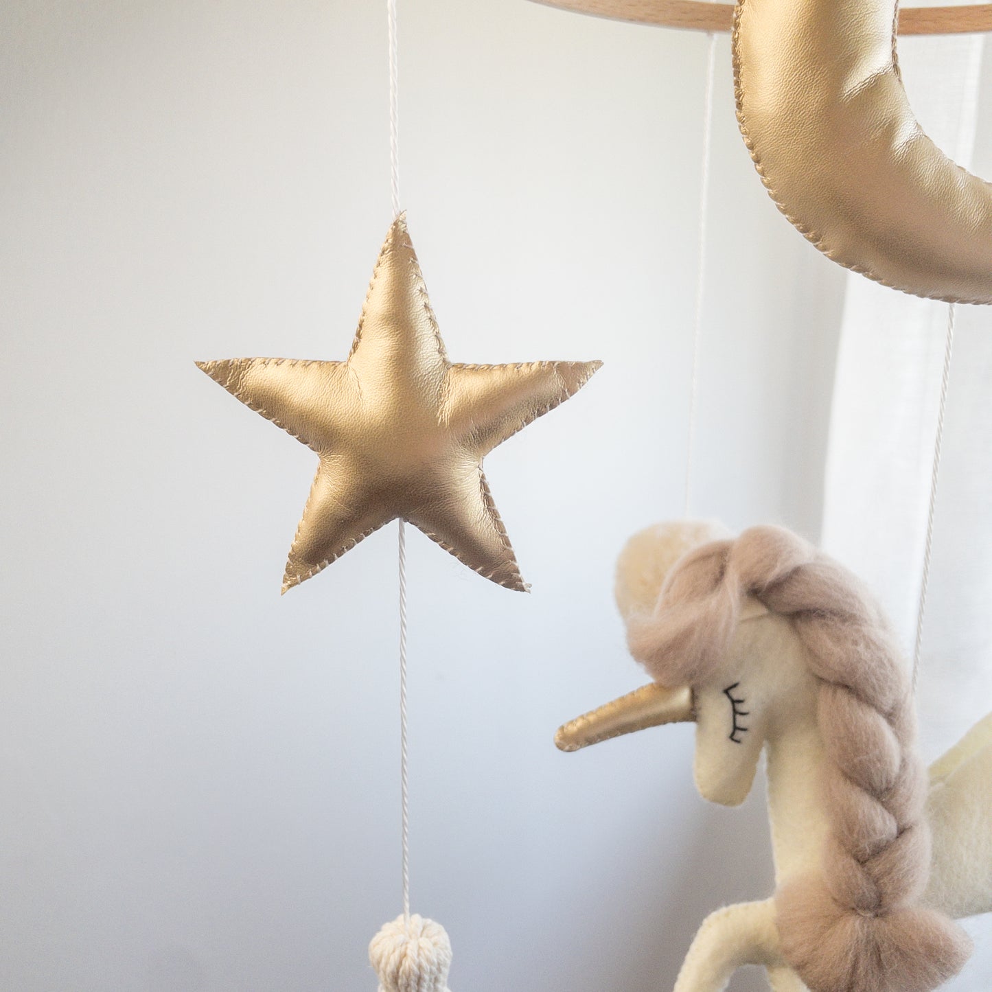Dettaglio stella cucita a mano color oro lucido che fa parte della giostrina per culla Unicorno