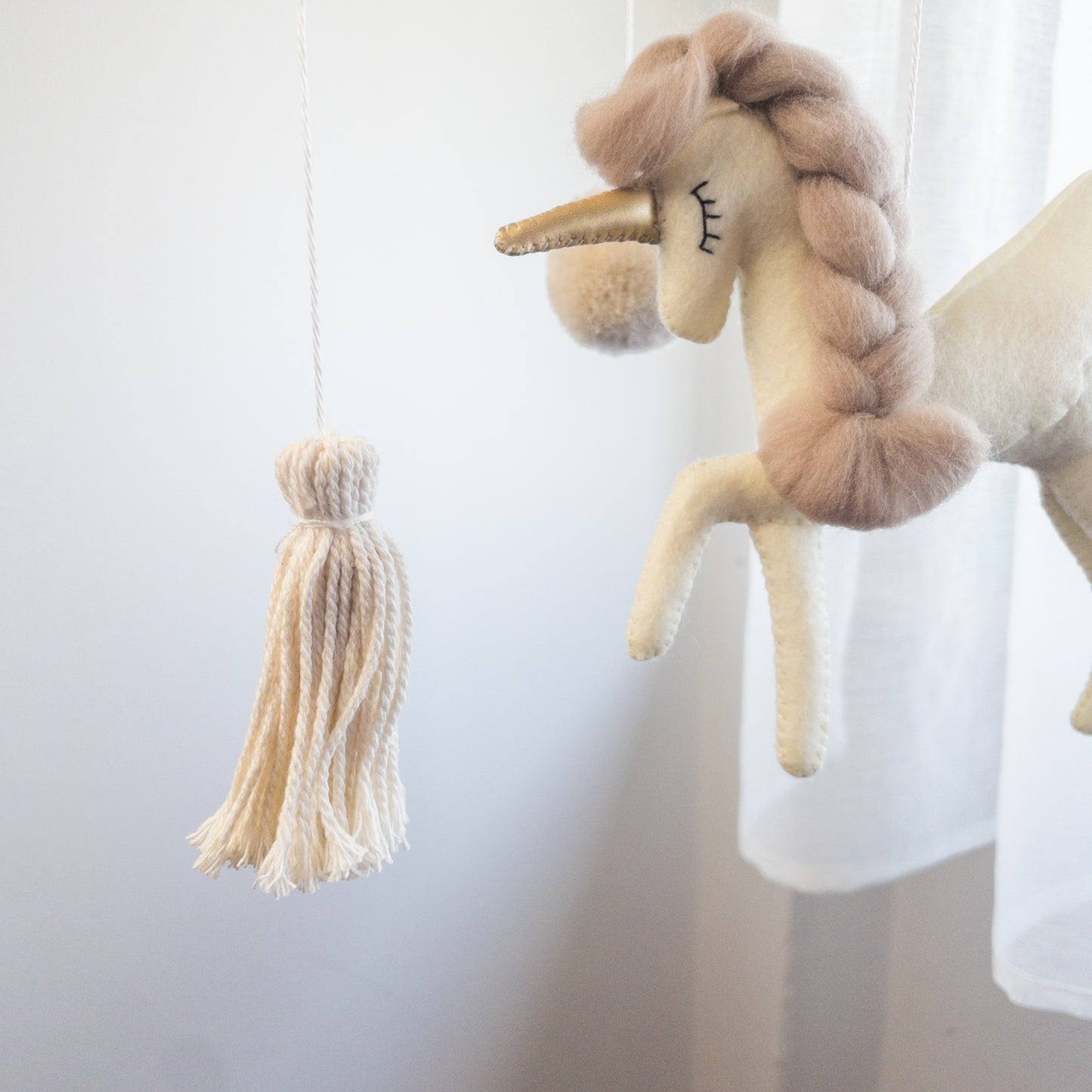 Unicorno in feltro con corpo bianco, coda e criniera con treccia beige, bellissimo ed elegante fa parte della giostrina per culla unicorno oro