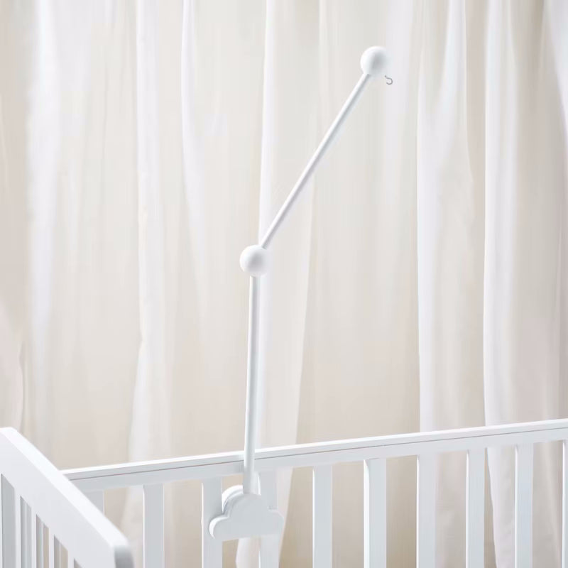 Supporto per giostrina culla Nuvola in legno bianco, montato su una culla con tende bianche. Ideale per appendere giostrine per neonato.