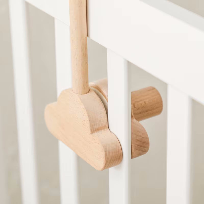 Dettaglio del supporto per giostrina culla Nuvola in legno di faggio con fissaggio sicuro a forma di nuvola su una sponda di lettino.