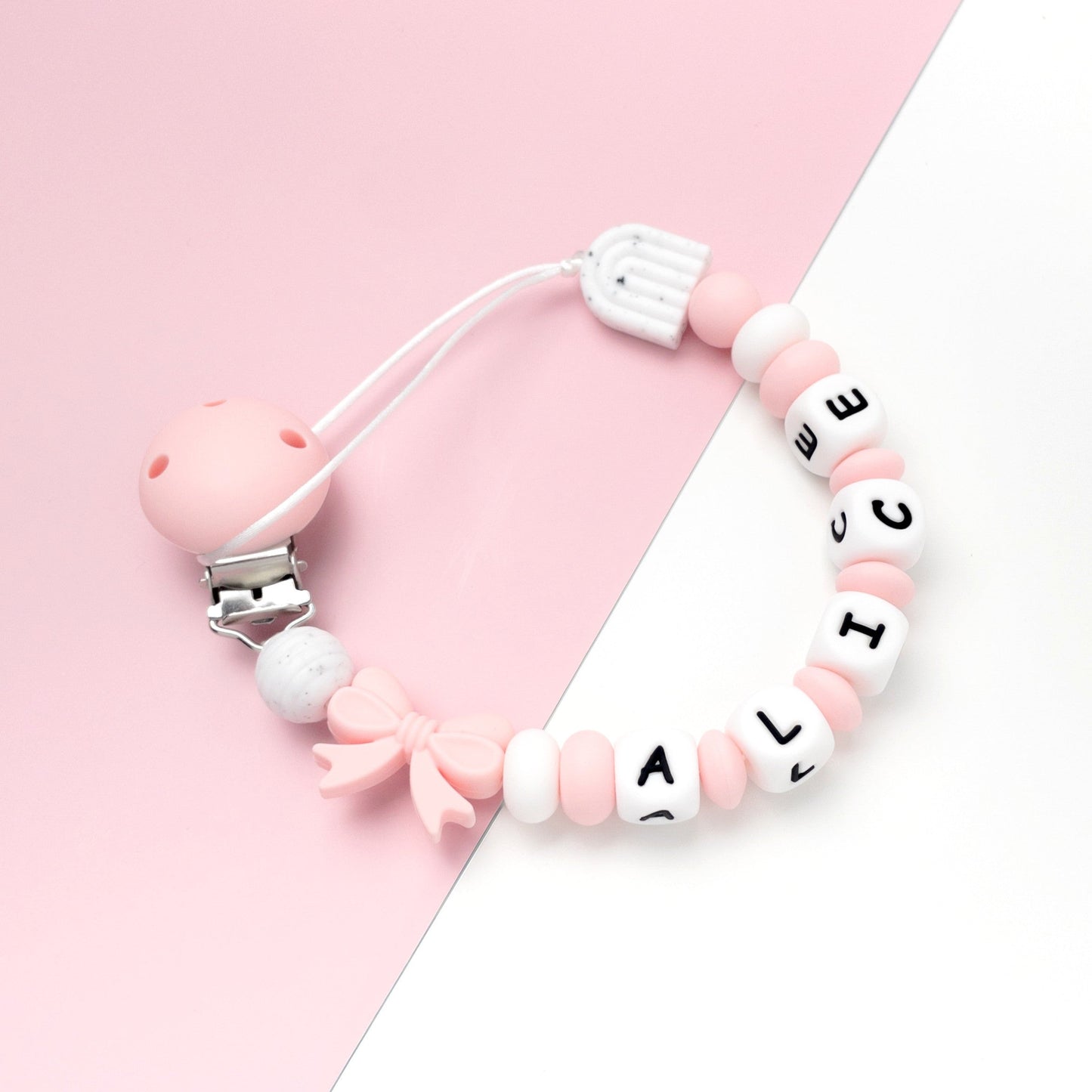 Catenella porta ciuccio rosa e bianca con nome alice, con clip rosa a scatto, 1 perlina fiocco rosa, 1 perlina arcobaleno bianca e nera