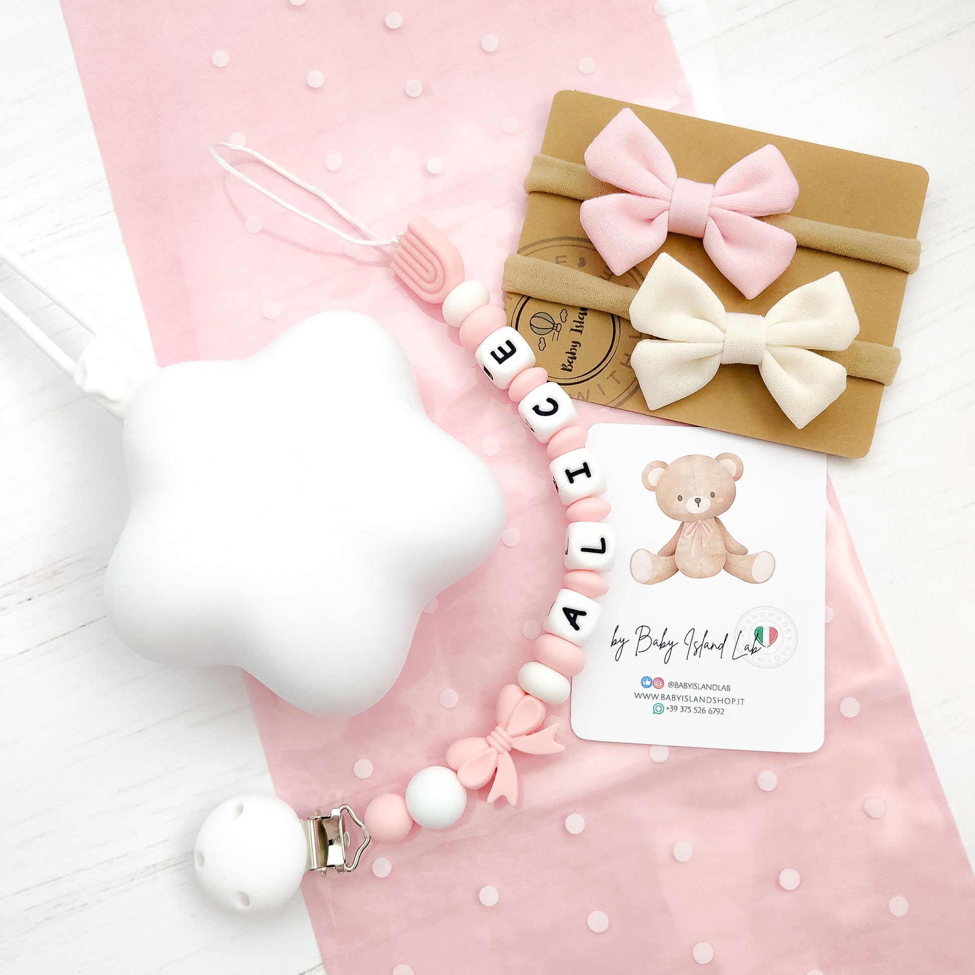 Set regalo neonata paersonalizzato con catenella porta ciuccio con nome E perline a forma di fiocco e arboleno, custodia a forma di stella bianca in siliocne e 2 fasce per neonata con fiocco a farfalla.