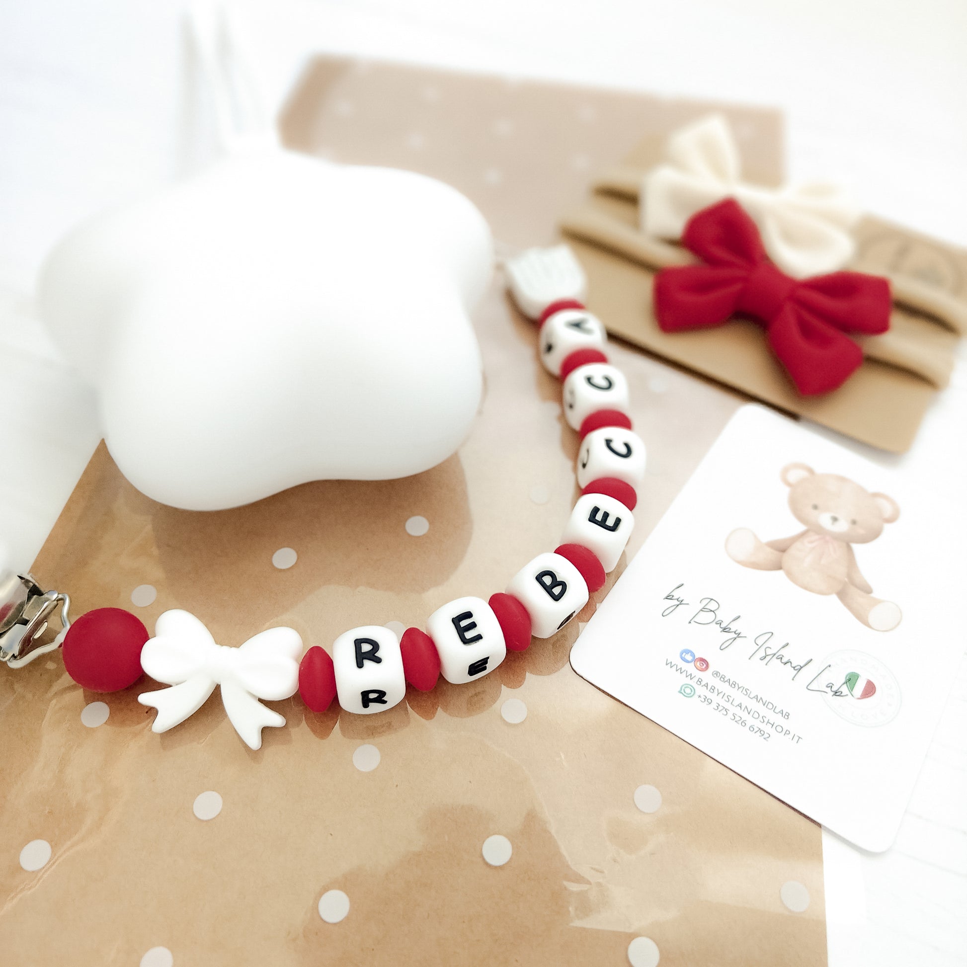 Scatola regalo nascita contenente accessori neonata: porta ciuccio stella, catenella personalizzata e fasce con fiocchi eleganti.