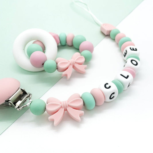 Set regalo Anello massaggiagengive dentizione Candy Collection™️ in silicone BPA free con perline color pastello e clip porta ciuccio personalizzata.
