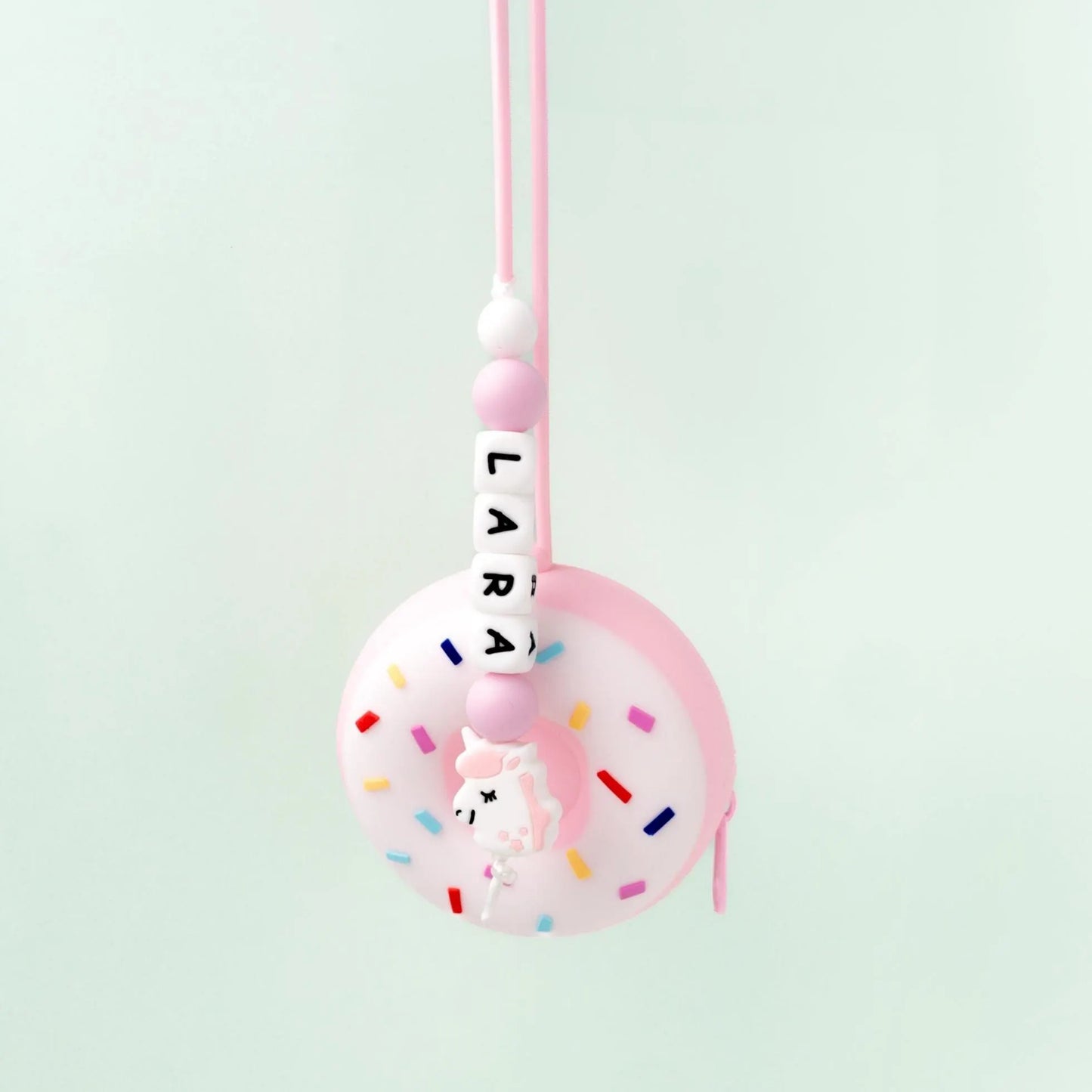 Ciondolo borsa del cambio per neonato portaciuccio e piccoli accessori, a forma di donut rosa (o verde) con glassa bianca e zuccheri colorati, con zip in silicone alimentare senza BPA. Con laccio e nome personalizzato in silicone e decorazione unicorno.