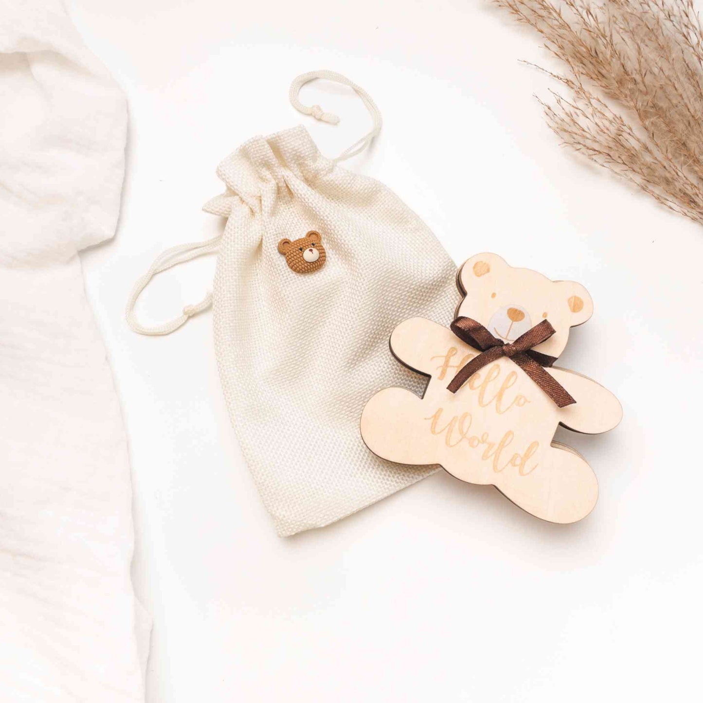 Set regalo neonato genere neutro Baby Bear con sacchetto in tessuto e decorazione in legno a forma di orsetto con fiocco marrone e scritta 'Hello World'.