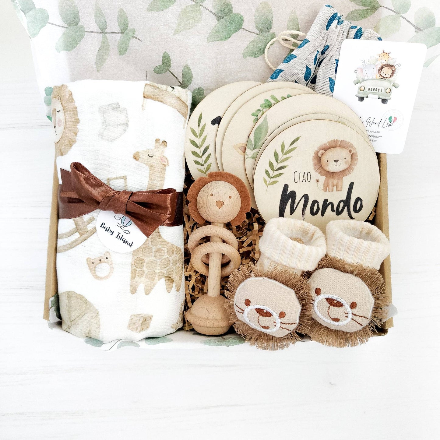 Scatola con set regalo per neonato a tema Safari con mussola XL, sonaglio in legno con testa di leone, carte pietre miliari traguardi mensili e calzine antiscivolo con decorazione testa di leone