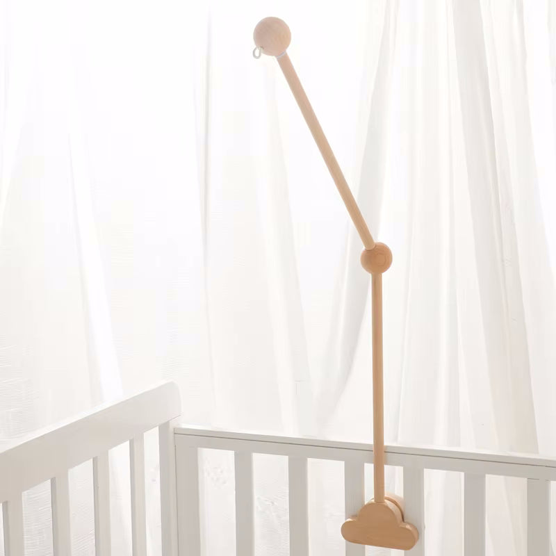 Supporto per giostrina culla Nuvola in legno naturale, fissato su una culla bianca con sfondo luminoso. Perfetto per decorare il lettino del neonato.