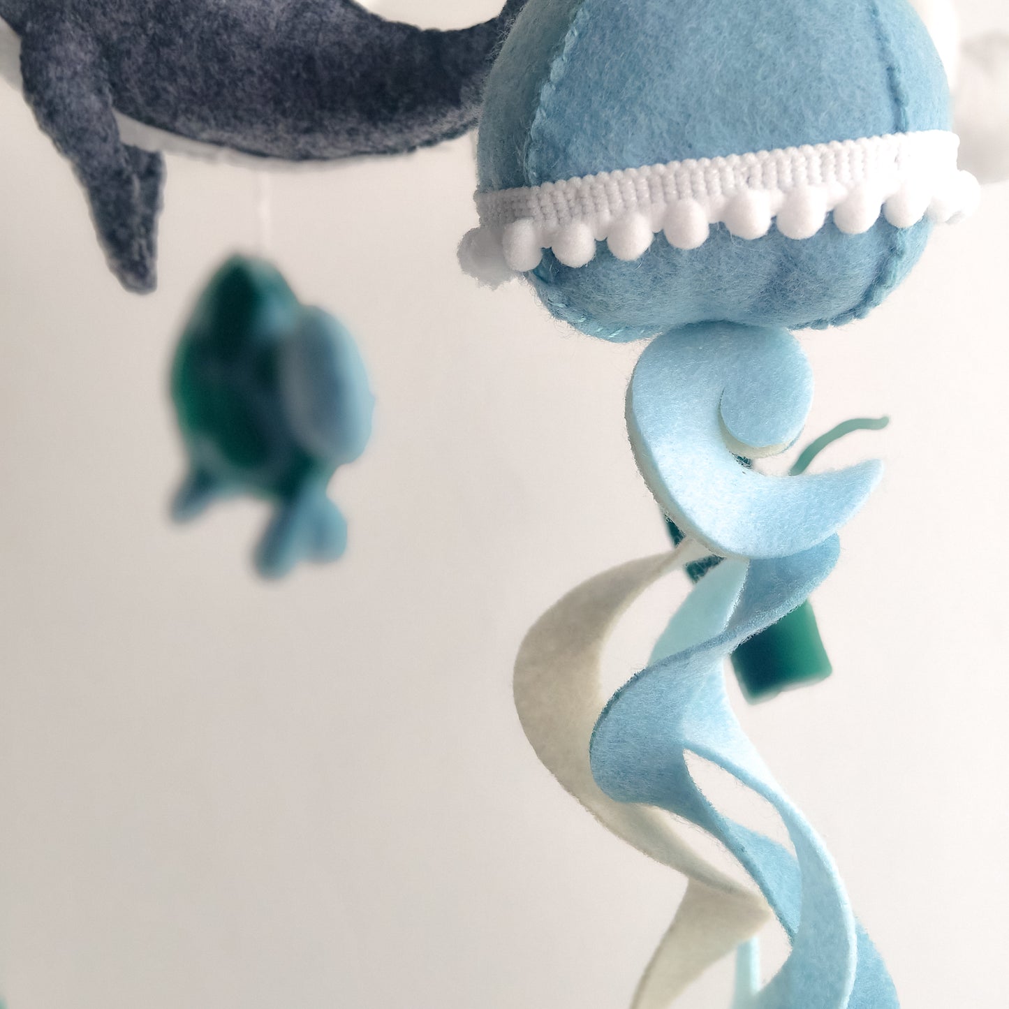 Decorazione sospesa per neonati con set completo di creature marine: grande balena centrale, polpo con tentacoli curvi, tartaruga marina e medusa con dettagli in pizzo. Ogni elemento è cucito a mano in feltro di alta qualità. Perfetto regalo per baby shower o lista nascita