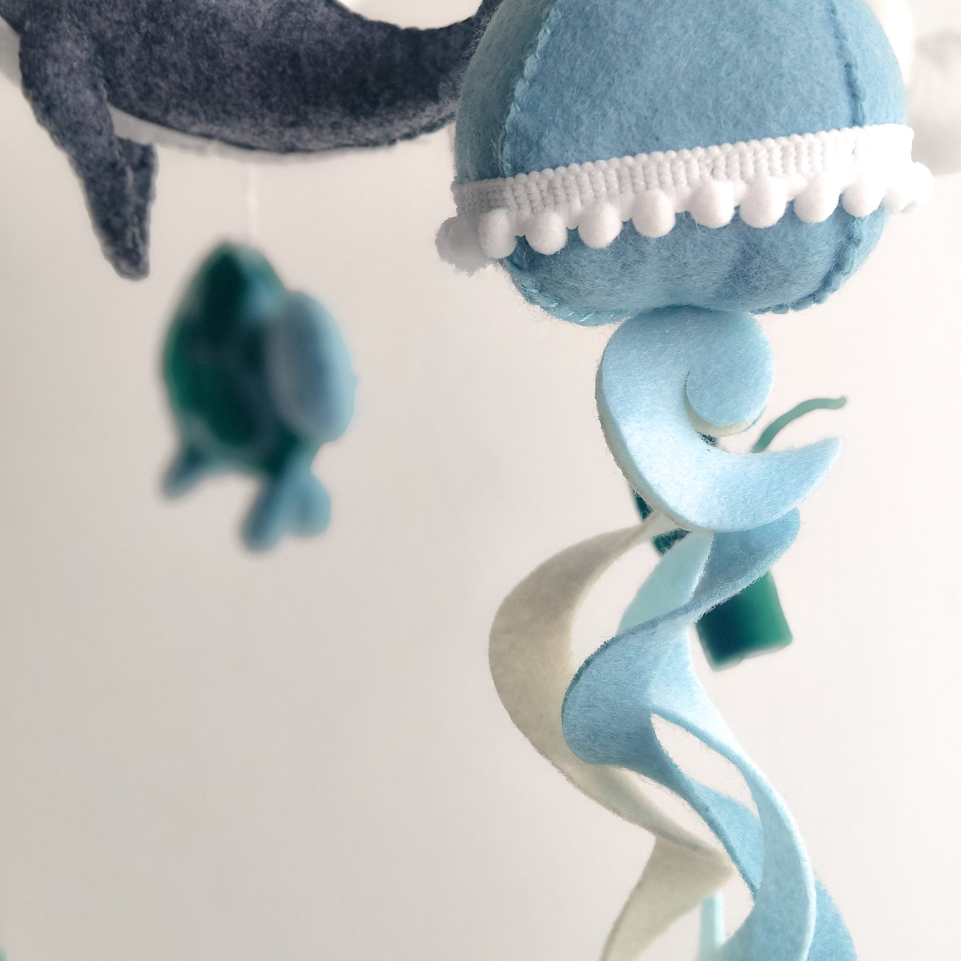Decorazione sospesa per neonati con set completo di creature marine: grande balena centrale, polpo con tentacoli curvi, tartaruga marina e medusa con dettagli in pizzo. Ogni elemento è cucito a mano in feltro di alta qualità. Perfetto regalo per baby shower o lista nascita