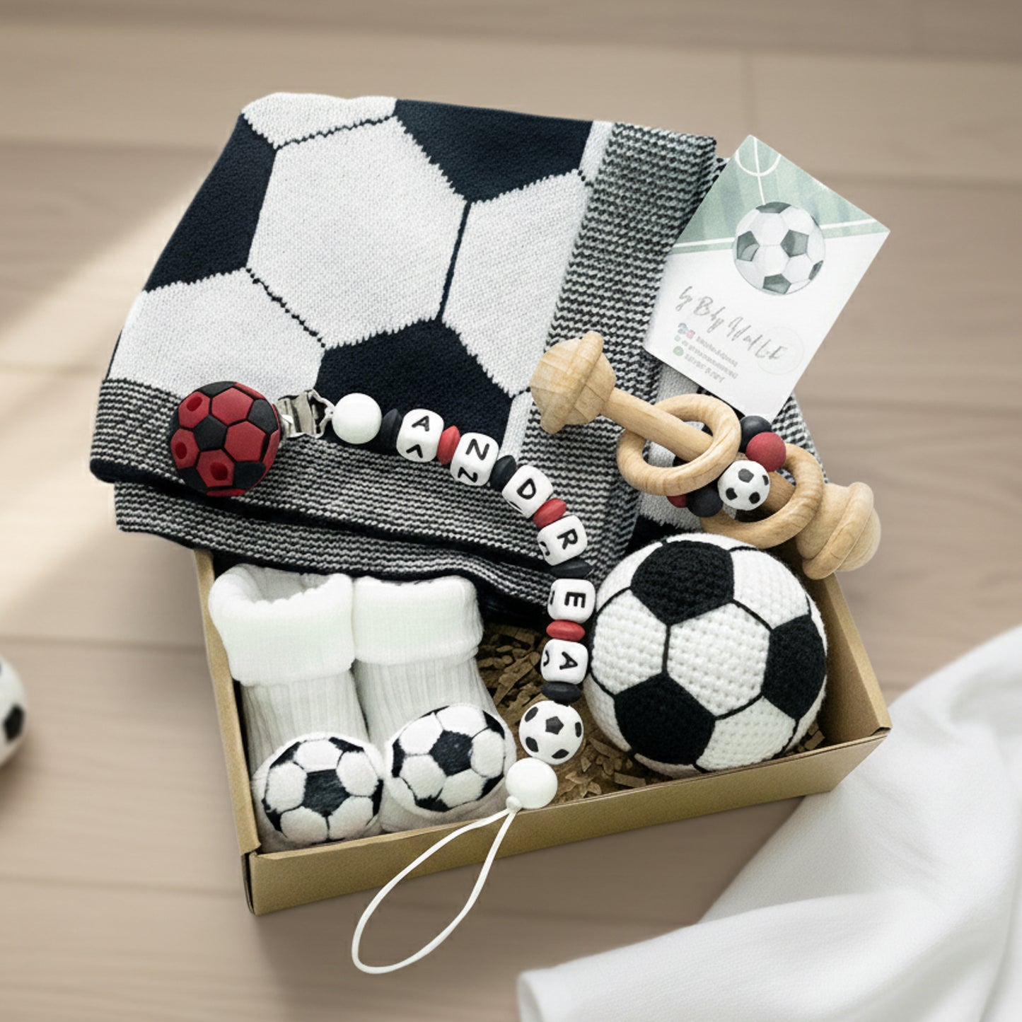 Un set regalo per neonato con coperta a tema calcio, catenella ciuccio personalizzato con nome, calzine da neonato e sonaglio ideale per piccoli amanti del calcio. Regalo neonato Napoli.