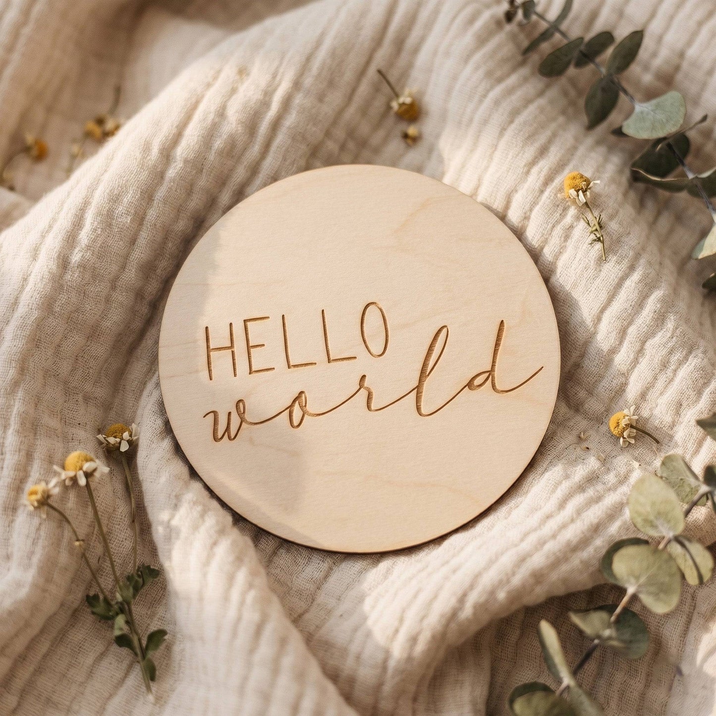 Dettaglio della card in legno Hello World con decorazioni di foglie e tessuto morbido