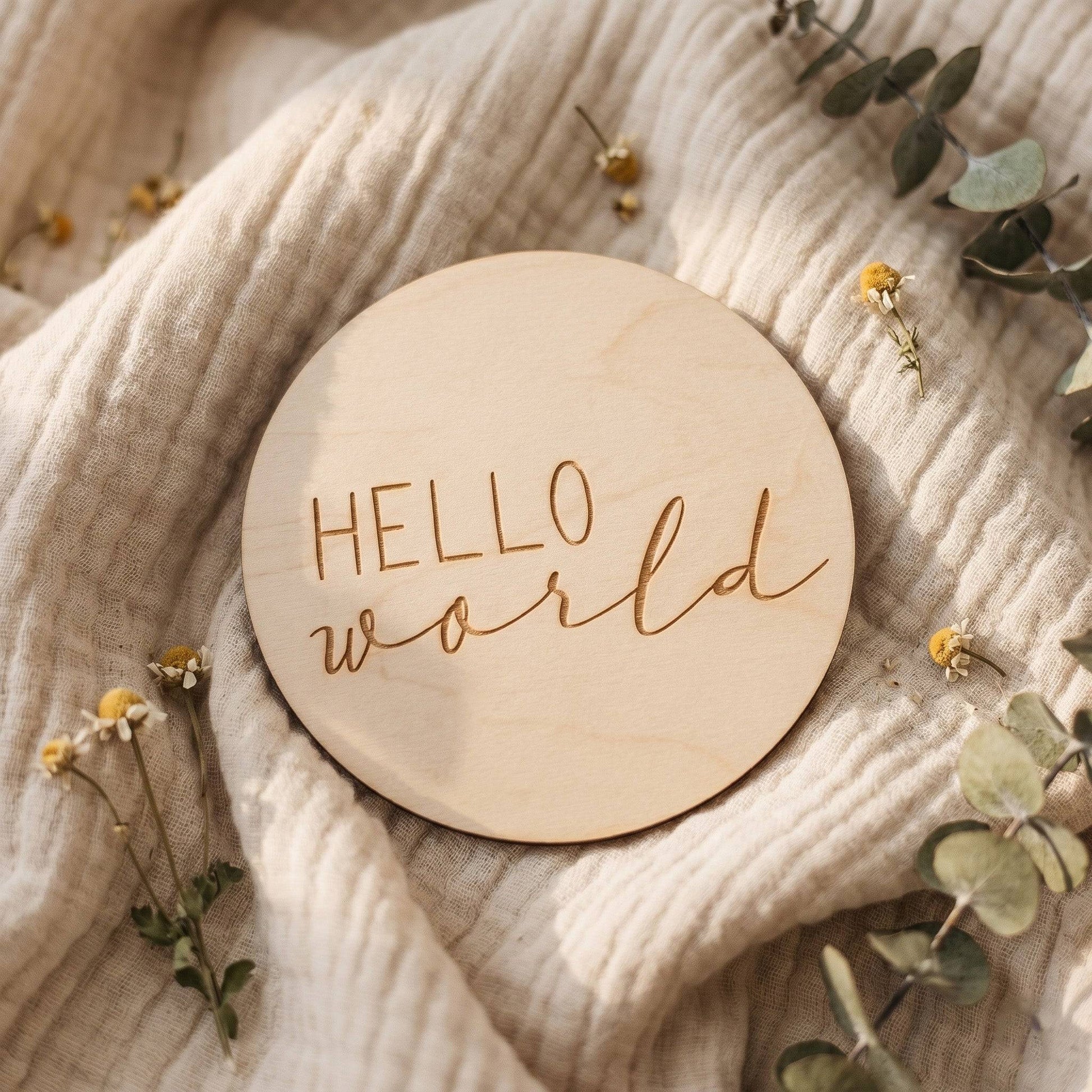 Dettaglio della card in legno Hello World con decorazioni di foglie e tessuto morbido