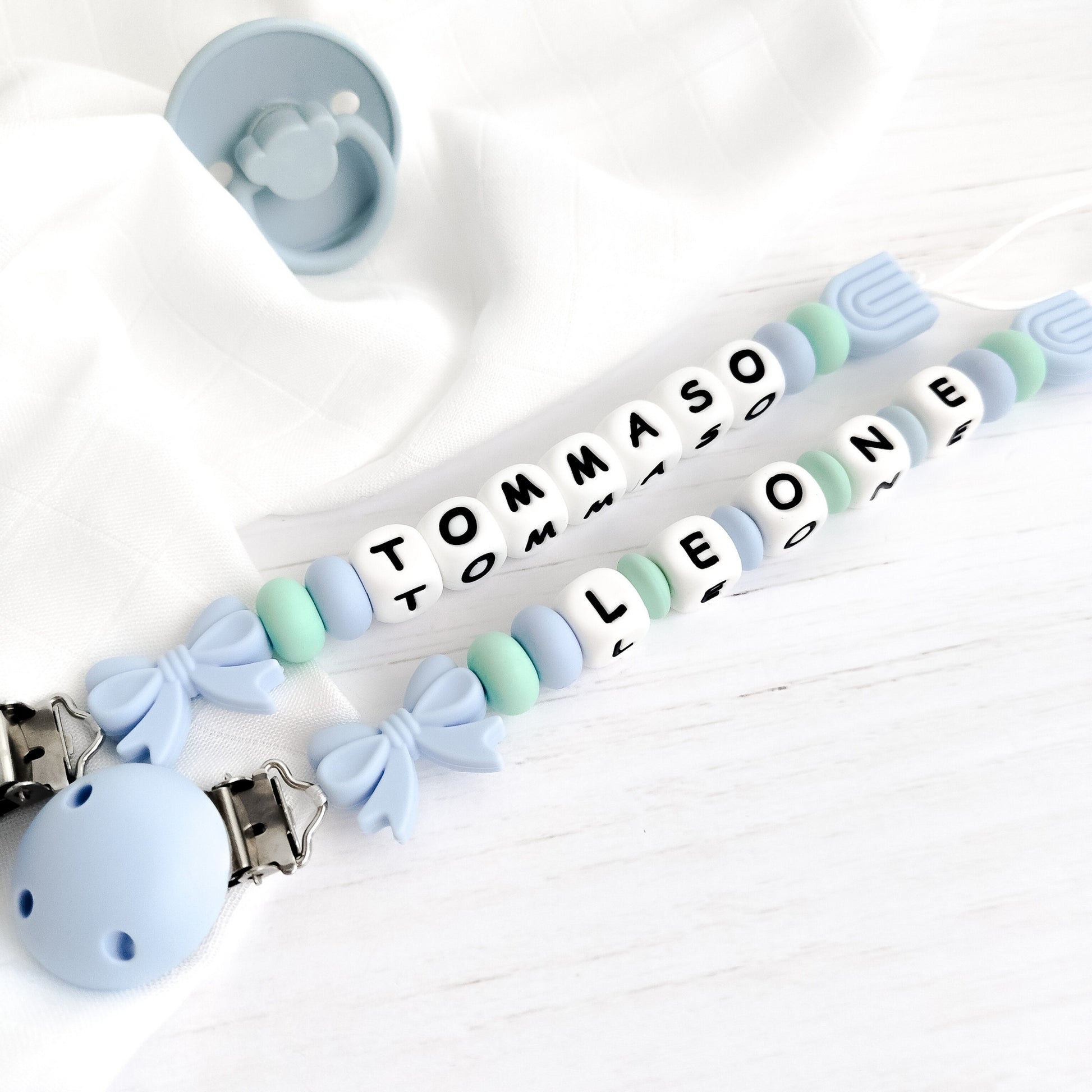 Catenella porta ciuccio azzurra e verde menta personalizzata con nome in silicone alimentare con fiocco e arcobaleno 