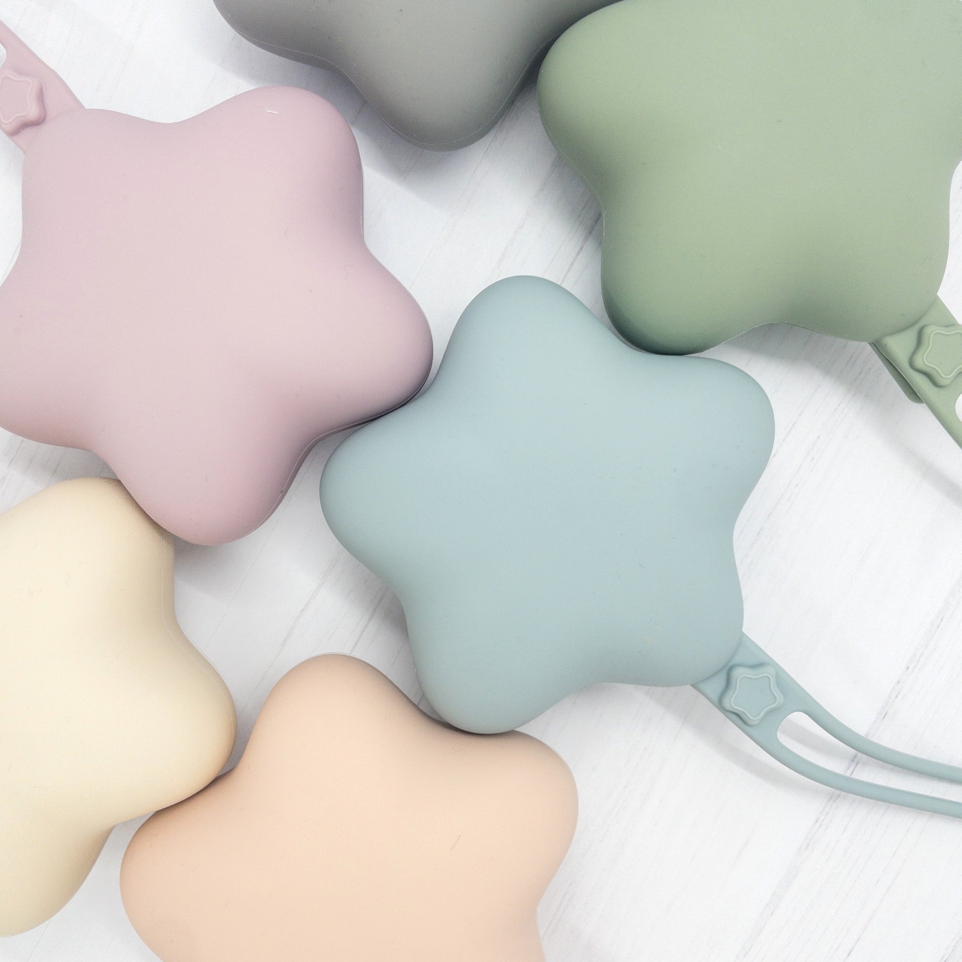 Custodia per ciuccio Stella in silicone in colori pastello come azzurro, rosa e verde, con laccio pratico per borse e passeggini.