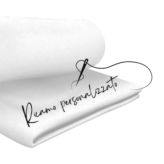 Ricamo personalizzato su tessuto bianco con ago e filo nero, ideale per personalizzare accessori Baby Island come mussole e bavaglini.