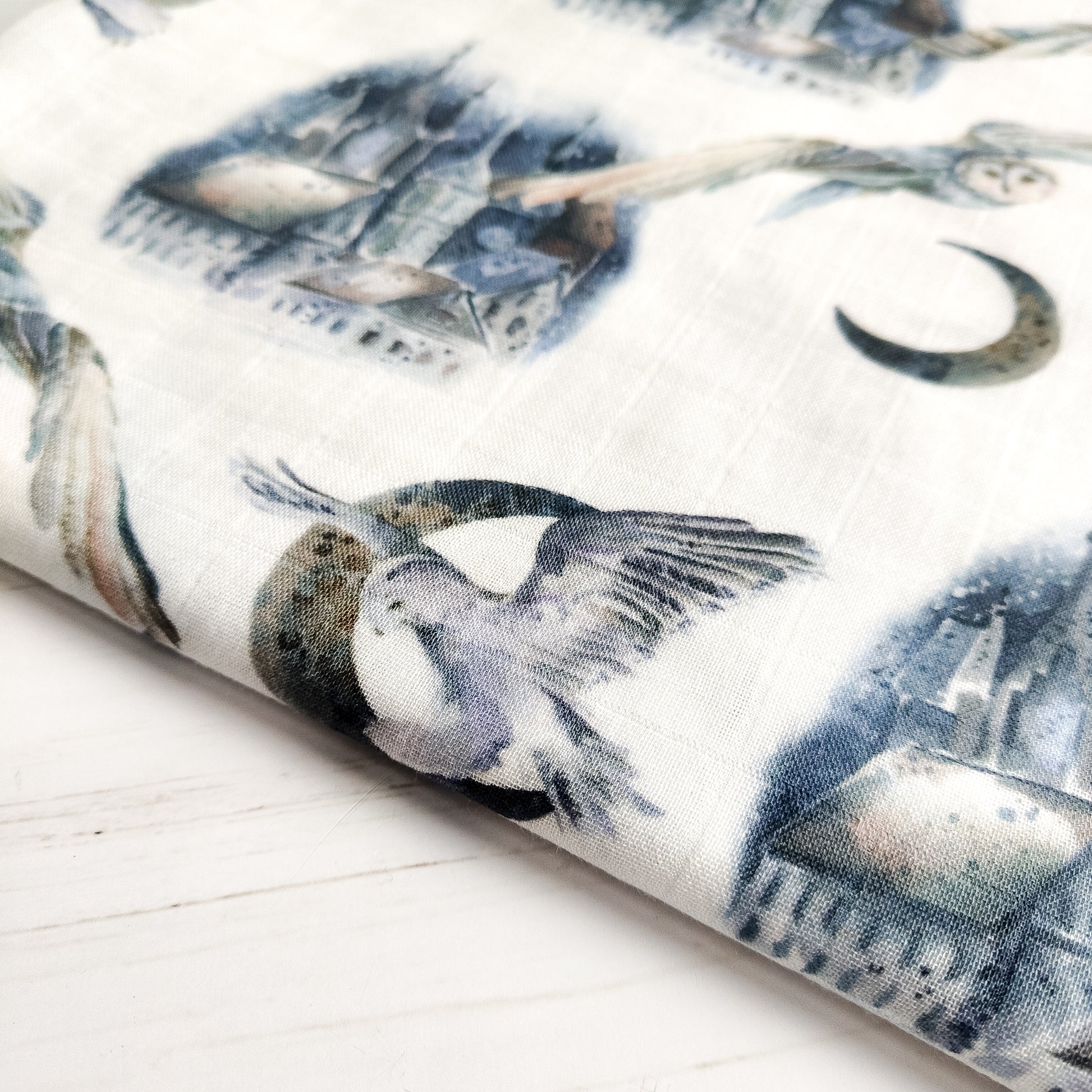 Particolare di tessuto con stampa di uccelli e natura, morbido cotone e bambù, ideale come copertina leggera per neonato.