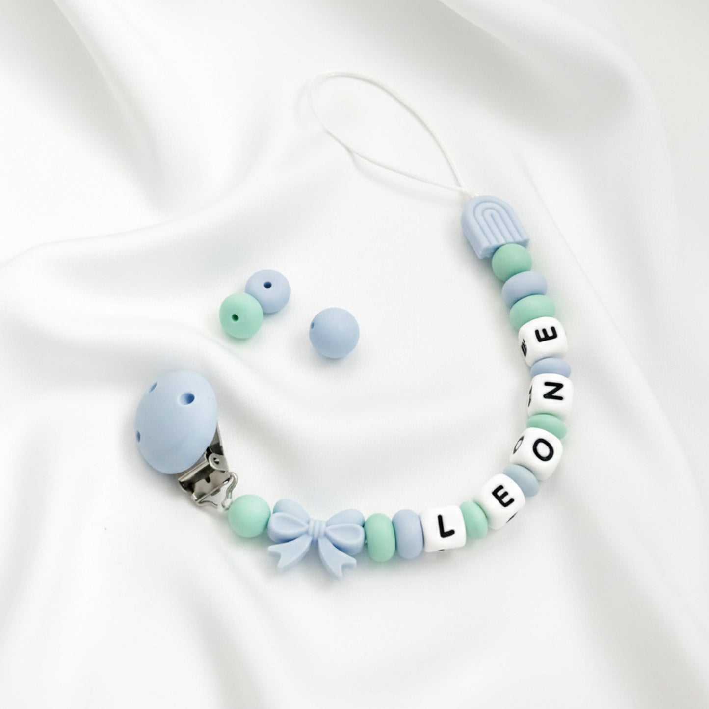 Catenella ciuccio personalizzata con nome LEONE in silicone azzurro e verde, ideale come regalo nuova nascita Baby Island.