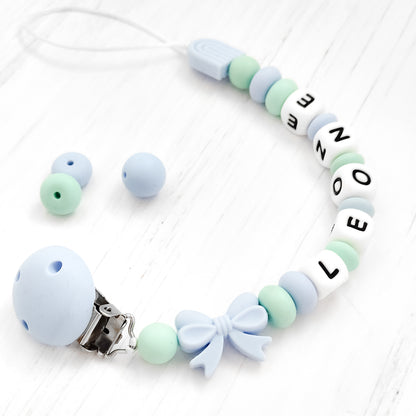 Dettaglio catenella ciuccio con nome LEONE in silicone BPA-free, colori pastello azzurro e verde, regalo originale Baby Island.