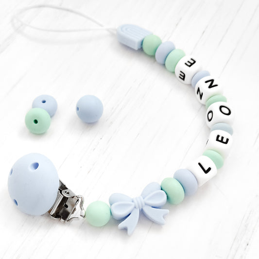 Dettaglio catenella ciuccio con nome LEONE in silicone BPA-free, colori pastello azzurro e verde, regalo originale Baby Island.