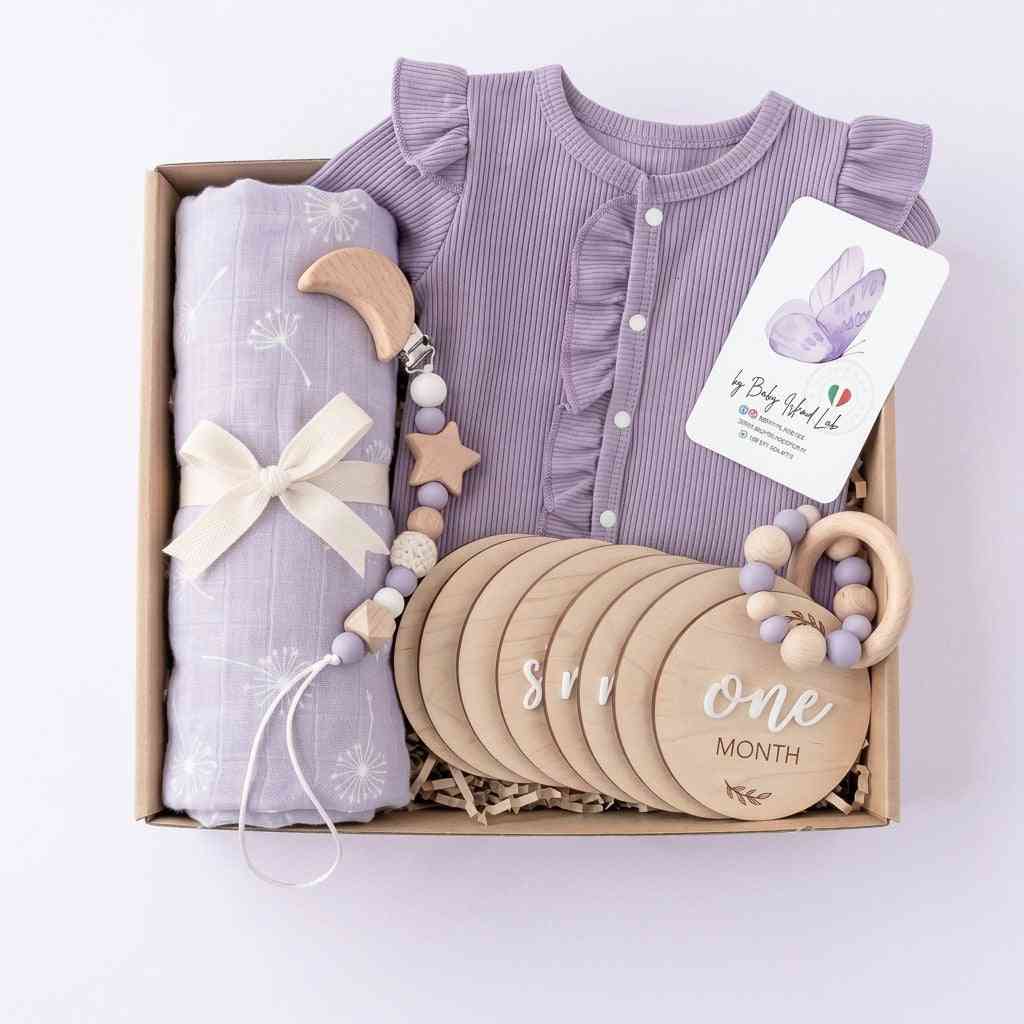 Set regalo neonato con body lilla in cotone, morbido ciuccio in legno, catenella con stelle e palline in silicone lilla, confezionato in scatola elegante
